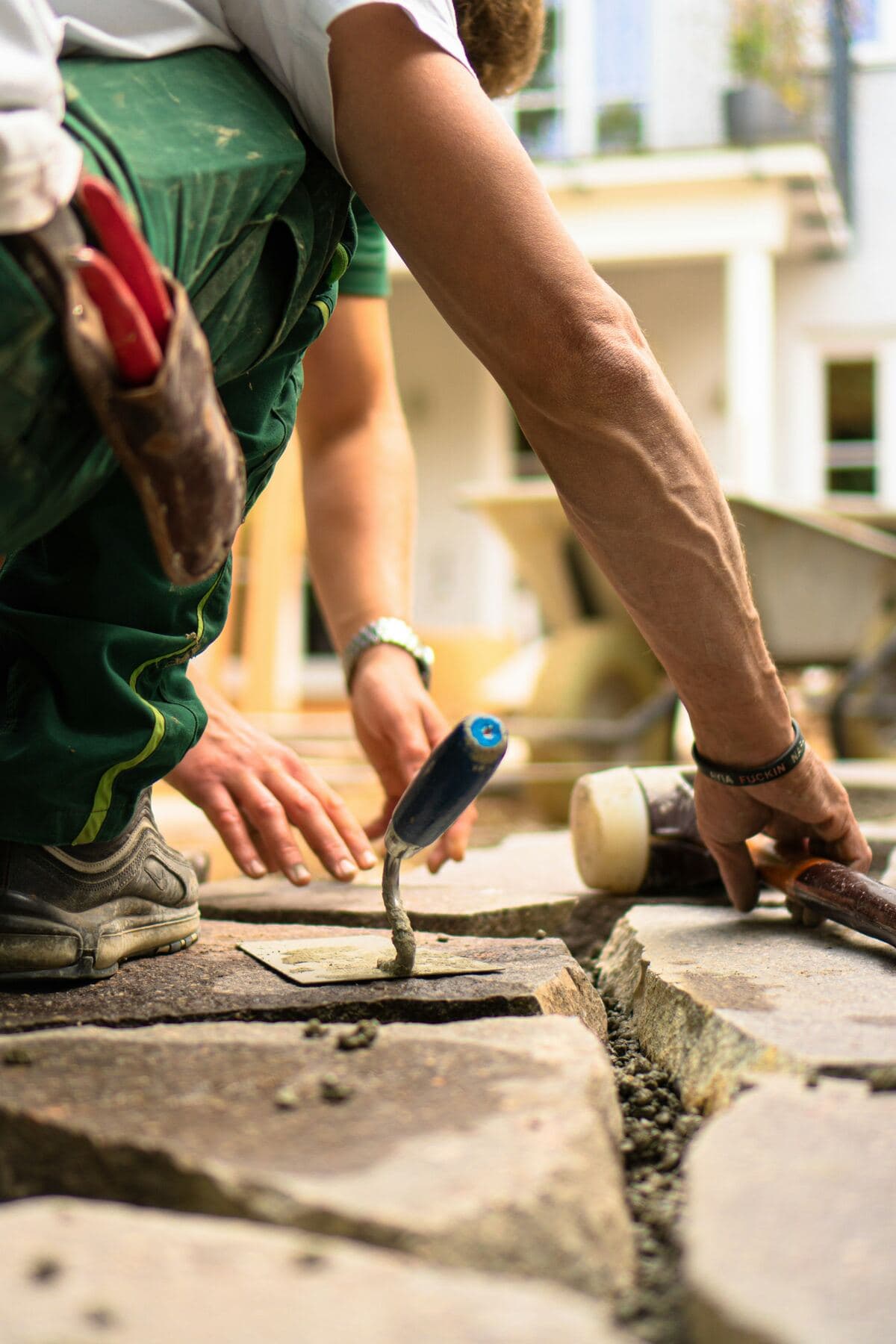 A landscaper fills the joints between stone slabs with a trowel.